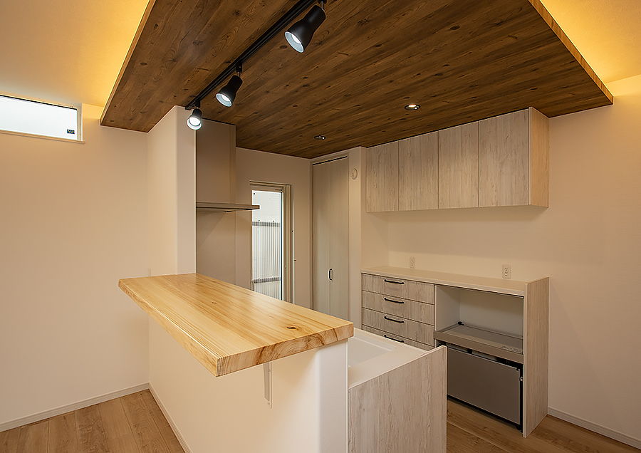 キッチンの天井の木目調のクロスにはおしゃれな間接照明｜京都・滋賀の注文住宅 天然木の家