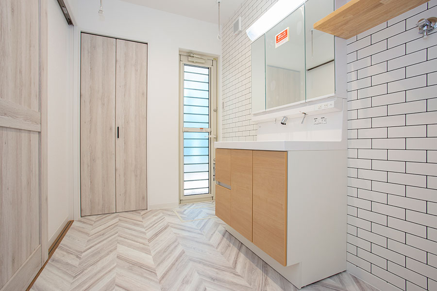 ヘリンボーン柄の床とタイル調壁紙が白でそろえられ清潔感がありながらもかわいい洗面室｜京都・滋賀の注文住宅 天然木の家
